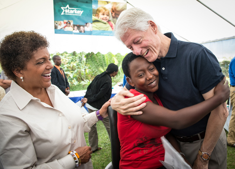 President Clinton hugs a young hearing-impaired girl who was fitted with a hearing aid at a Starkey Hearing Foundation event in Kigali, Rwanda. At left is Linda Johnson Rice, publisher of Ebony and Jet magazines. 